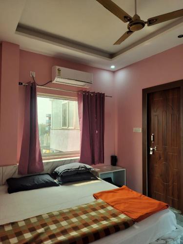 a bedroom with a bed with pink walls and a window at Tulsi Ganga Hostel in Rishīkesh
