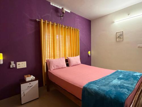 a bedroom with a bed with purple walls and yellow curtains at Mud apples in Varkala