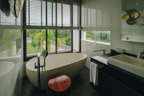 a bathroom with a tub and a sink at Porsampao Luxury Villa in Ban Khok Khilek