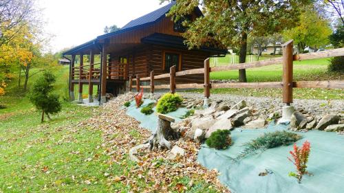 a log cabin with a garden in front of it at Chatka Pod Dębem in Rozdziele