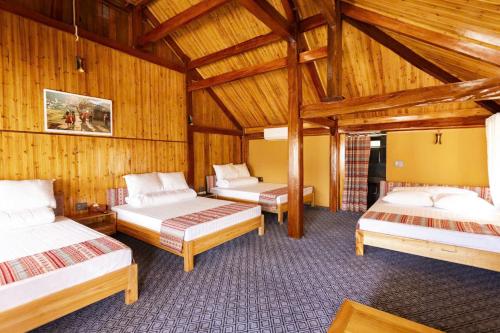 three beds in a room with wooden walls at Fullhouse Mộc Châu in Mộc Châu