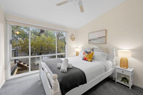 a bedroom with a white bed and a large window at Salty Haven in Moggs Creek