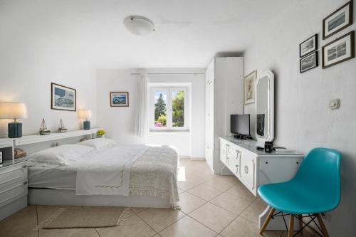 a white bedroom with a bed and a blue chair at Apartments Zoe in Bol