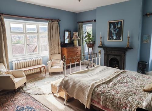 a bedroom with blue walls and a bed and a fireplace at Church Path Rooms in Minehead