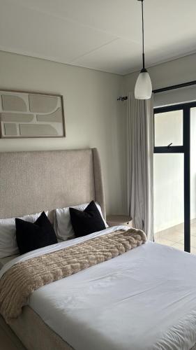 a bedroom with a large white bed with black pillows at Elara in Sandton