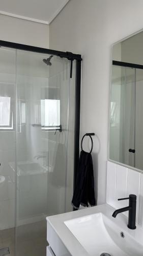 a bathroom with a shower and a sink and a mirror at Elara in Sandton