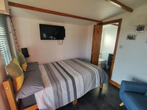 a bedroom with a bed and a tv on the wall at Butterfly Cabin in Millom
