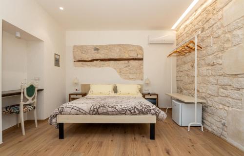 a bedroom with a bed and a brick wall at Terrazza Campailla in Modica