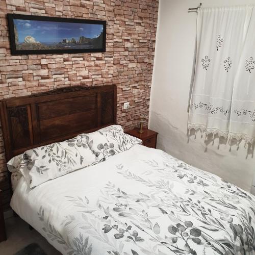 a bedroom with a bed with a tv on a brick wall at Casita de Aldea in Sotrondio