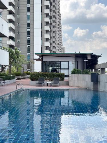 a swimming pool with two chairs in front of a building at Bann-Kun Impact Muang Thong 2BR Condo Wi-Fi MRT Pink Near Airport DM