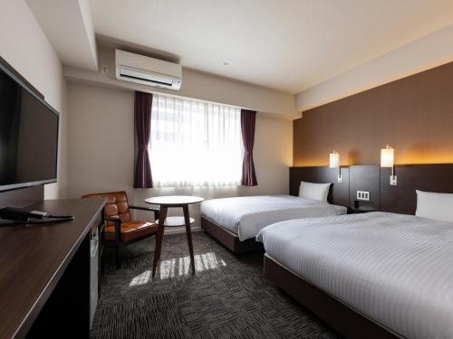 a hotel room with two beds and a flat screen tv at KOKO HOTEL Osaka Shinsekai - formerly Hotel Wing Premium Osaka Shinsekai in Osaka