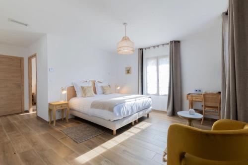 a white bedroom with a bed and a table at Le Baguier in La Roquebrussanne