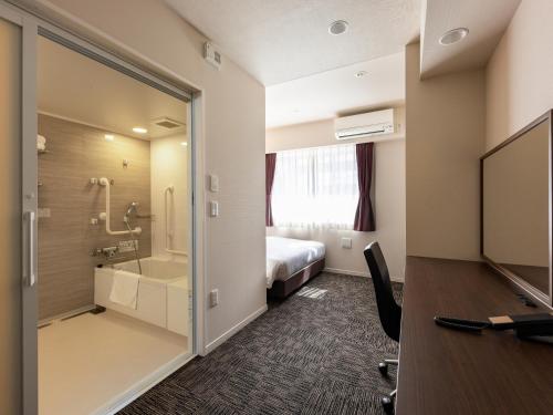 a hotel room with a bed and a tv at KOKO HOTEL Osaka Shinsekai - formerly Hotel Wing Premium Osaka Shinsekai in Osaka