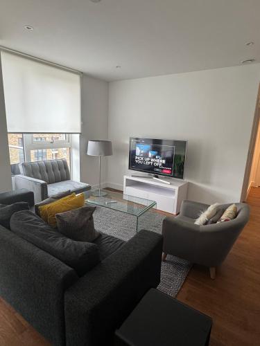 a living room with two couches and a flat screen tv at 2 bedroom 2 bath 1 ensuite in Roya Asenal beautiful views & parking in Woolwich