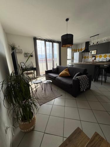 a living room with a black couch and a kitchen at Le 305 Beauvert Parking Gratuit in Grenoble