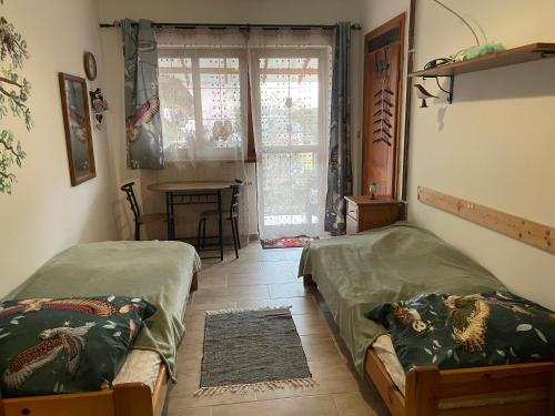 two beds in a room with a table and a window at U Sovičky in Olešník
