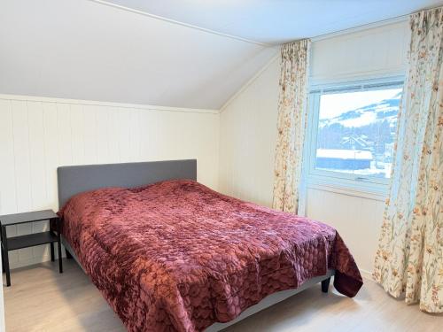 a bedroom with a bed with a red comforter and a window at Spacious apartment in Follebu in Aulestad