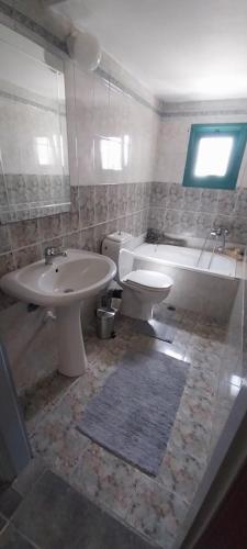 a bathroom with a sink and a toilet and a tub at Sidari High Street Apartment in Sidari