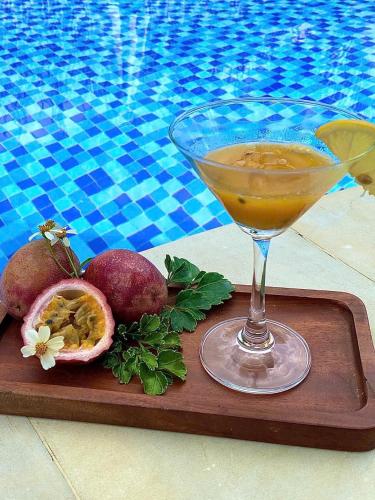 a drink sitting on a wooden tray next to a pool at Mekong Silt Ecolodge - Swimming Pool & Free Breakfast in Can Tho