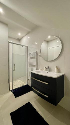 a bathroom with a sink and a shower with a mirror at L'Echo du Bonheur in Vaumas