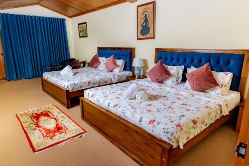 two beds in a room with blue curtains at Glenbourne Bungalow in Galaha Town