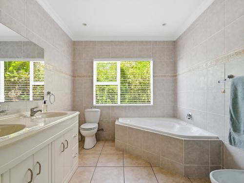 a bathroom with a tub and a toilet and a sink at Coney Glen Penthouse in Knysna