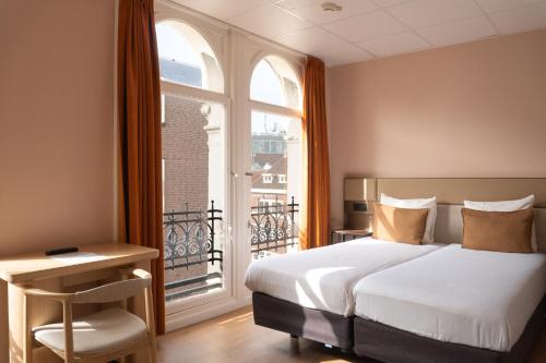 a bedroom with a bed and a large window at CS Hotel in Amsterdam