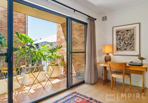 an open living room with a desk and a sliding glass door at West End Apartments in Fremantle