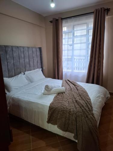 a bedroom with a bed with a blanket and a window at Baraka Stay,Kenol,Gitura,Murang'a in Gitura