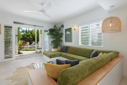 a living room with a green couch and a table at Pandanus Cottage in Port Douglas