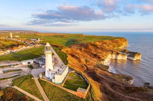 an aerial view of a lighthouse on a cliff at Jay Valley 17 Thornwick Bay in Flamborough