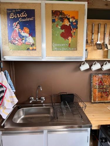 a kitchen counter with a sink and posters on the wall at The Termite Mound - Termite Tented in Khwai