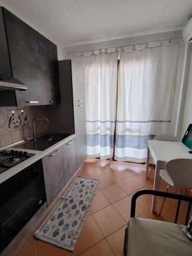 a kitchen with a stove and a table and a window at Casa Ventaglio Verde in Valledoria