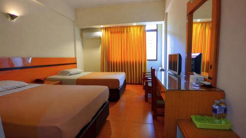 a hotel room with two beds and a television at Paradise Hotel in Tanjung Pinang