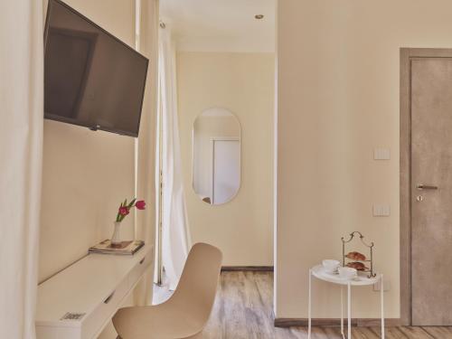 a white living room with a chair and a tv at Hotel L'Aretino in Arezzo