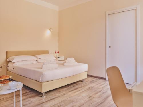 a white bedroom with a bed and a table at Hotel L'Aretino in Arezzo