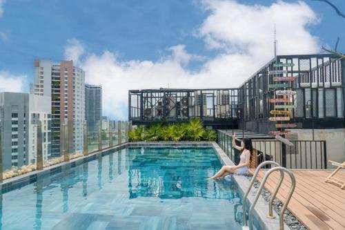 a woman sitting next to a swimming pool on top of a building at Tropical Dorm Hostel Da Nang by Haviland in Danang