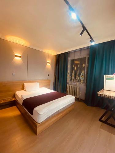 a bedroom with a large bed and a blue curtain at Ayanchin Hotel in Ulaanbaatar