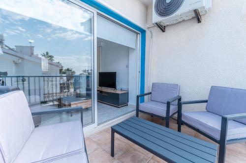 a balcony with two chairs and a couch and a television at Beach Escape Beachfront Apartment in Pyla