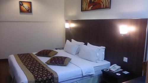 um quarto de hotel com uma cama com um telefone em Hotel & Apartment Ambassador 3 em Labuan