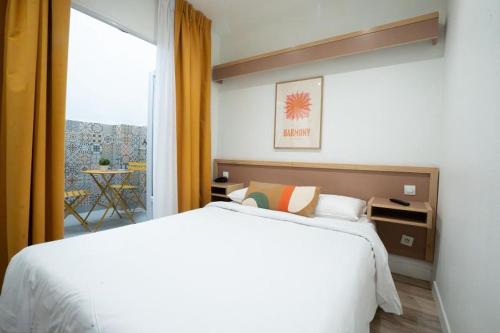 a bedroom with a white bed and a large window at Hôtel Edgar Quinet in Paris