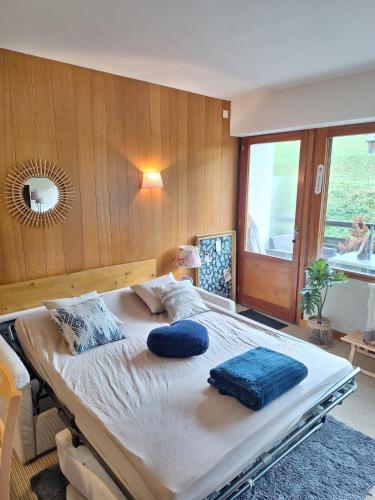 a bedroom with a large bed with blue pillows on it at Le Ptit Beau Jus in Aillon-le-Jeune