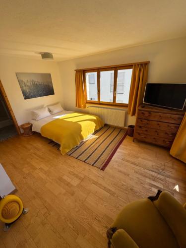 a bedroom with a yellow bed and a flat screen tv at Waldheim Laax Pension in Laax