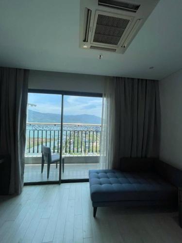 a living room with a couch and a large window at Golden Bay Danang in Danang