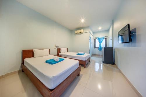 a bedroom with two beds and a tv in it at Chaorua Hotel in Ko Phra Noi