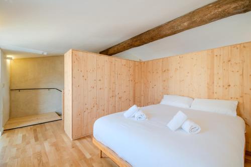 a bedroom with a white bed and wooden walls at Flateli Cornellà del Terri in Santa Llogaia del Terri