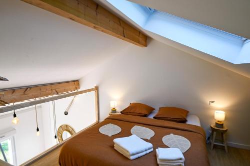 a bedroom with a large bed with two towels on it at La Petite Sommière in Besançon