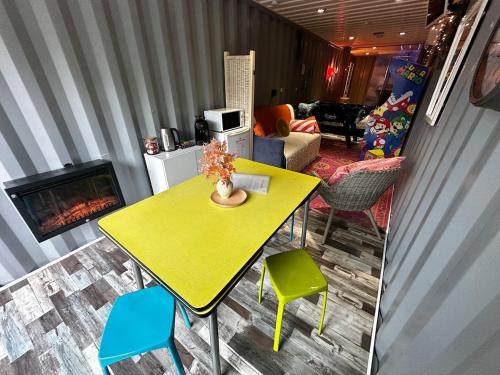 a yellow table and chairs in a living room with a fireplace at Séjour insolite dans un Container aménagé à Berck avec Borne d'arcade et Babyfoot in Berck-sur-Mer
