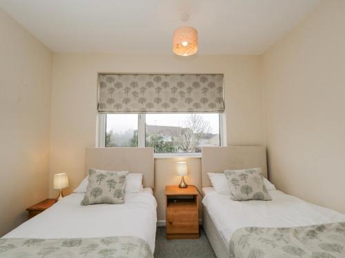 two beds in a room with a window at Lavender Harmony House in Swindon