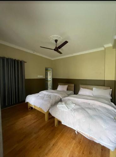 two beds in a bedroom with a ceiling fan at Hotel Lake Heaven in Deorāli